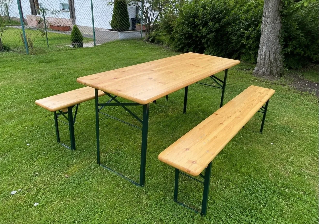 Klassische Festzeltgarnitur aus Holz auf Rasenfläche